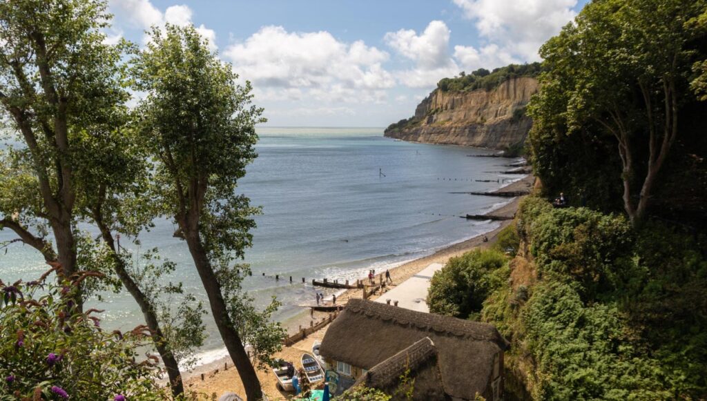 Shanklin Beach on the Isle of Wight showing the wooden groynes and people walking on the sand.