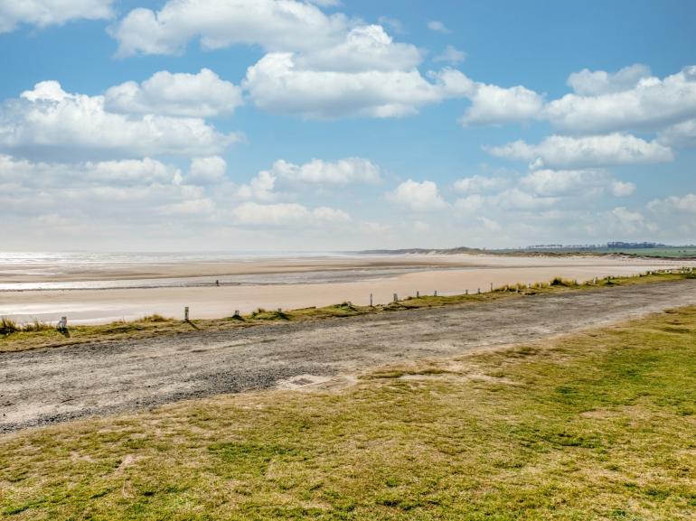 Northumberland empty sandy beach with sand dunes in the distance.