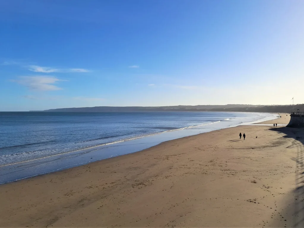 Couple walking along Filey Beach in the sunshine