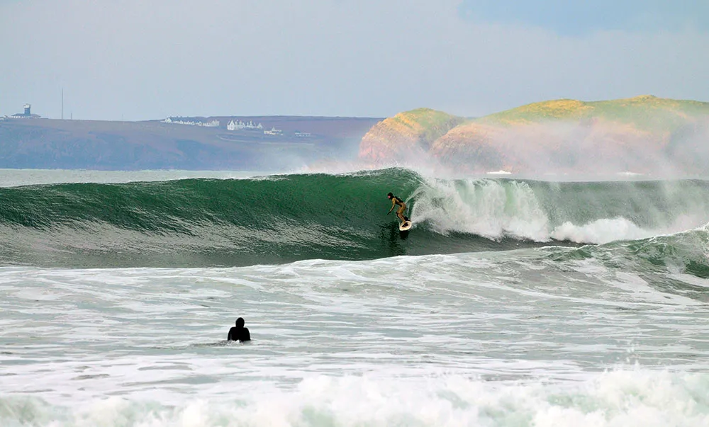 Surfer on a curling wave at Freshwater West in Pembrokeshire