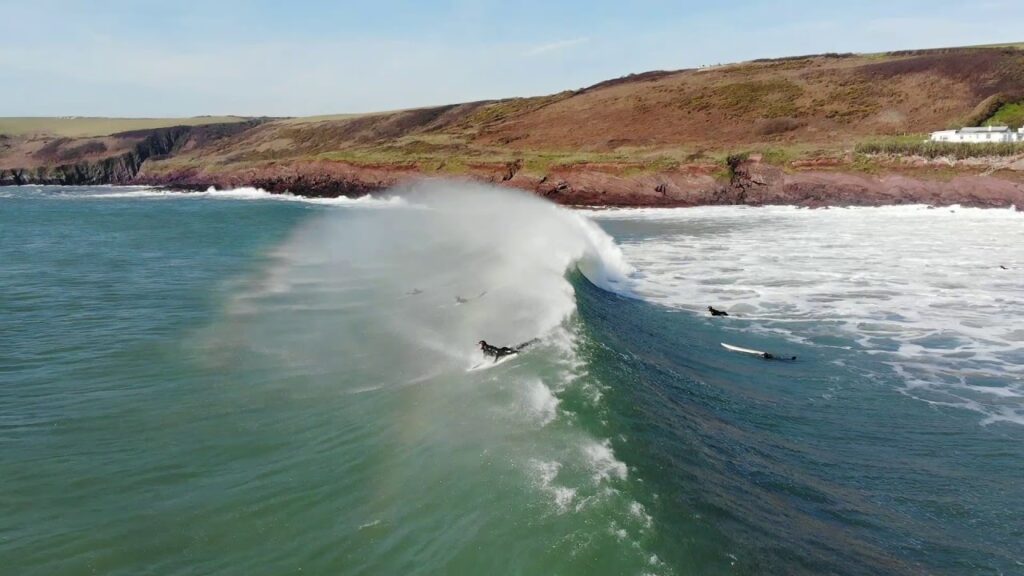 Several surfers on a wave at Manorbier Beach in Pembrokeshire