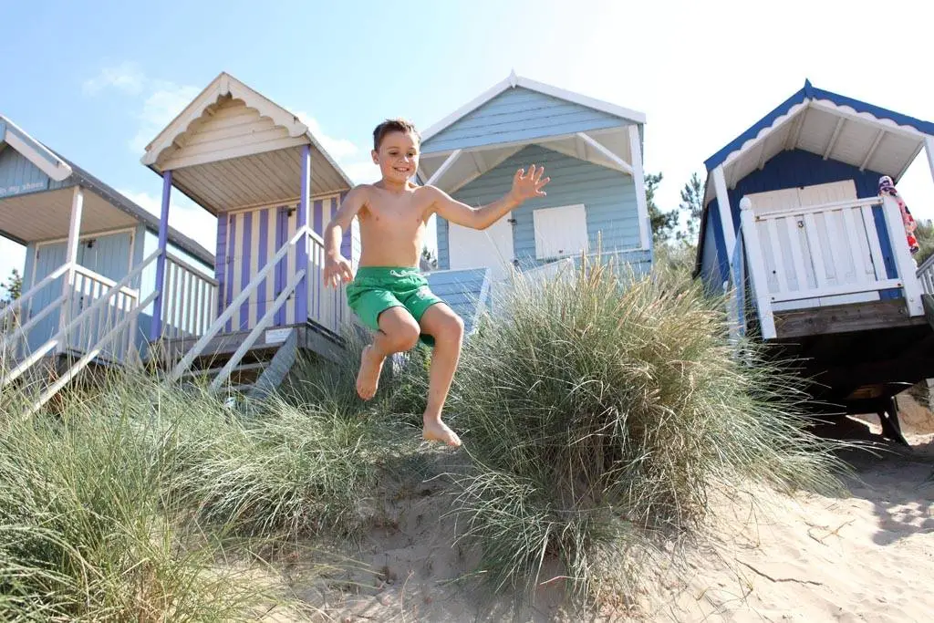 Boy jumping in the sand dunes on the beach.