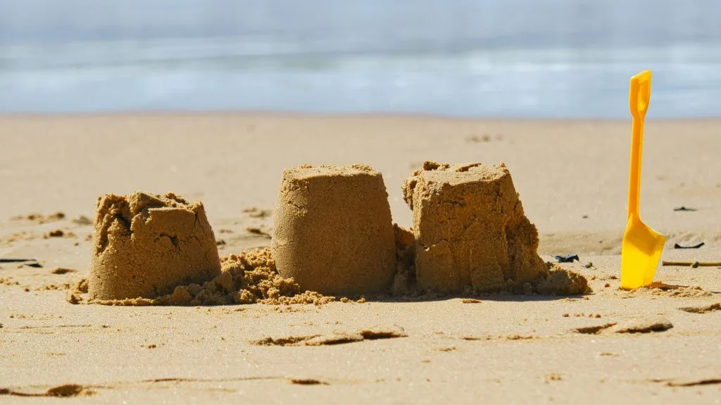 Three small sandcastles and spade