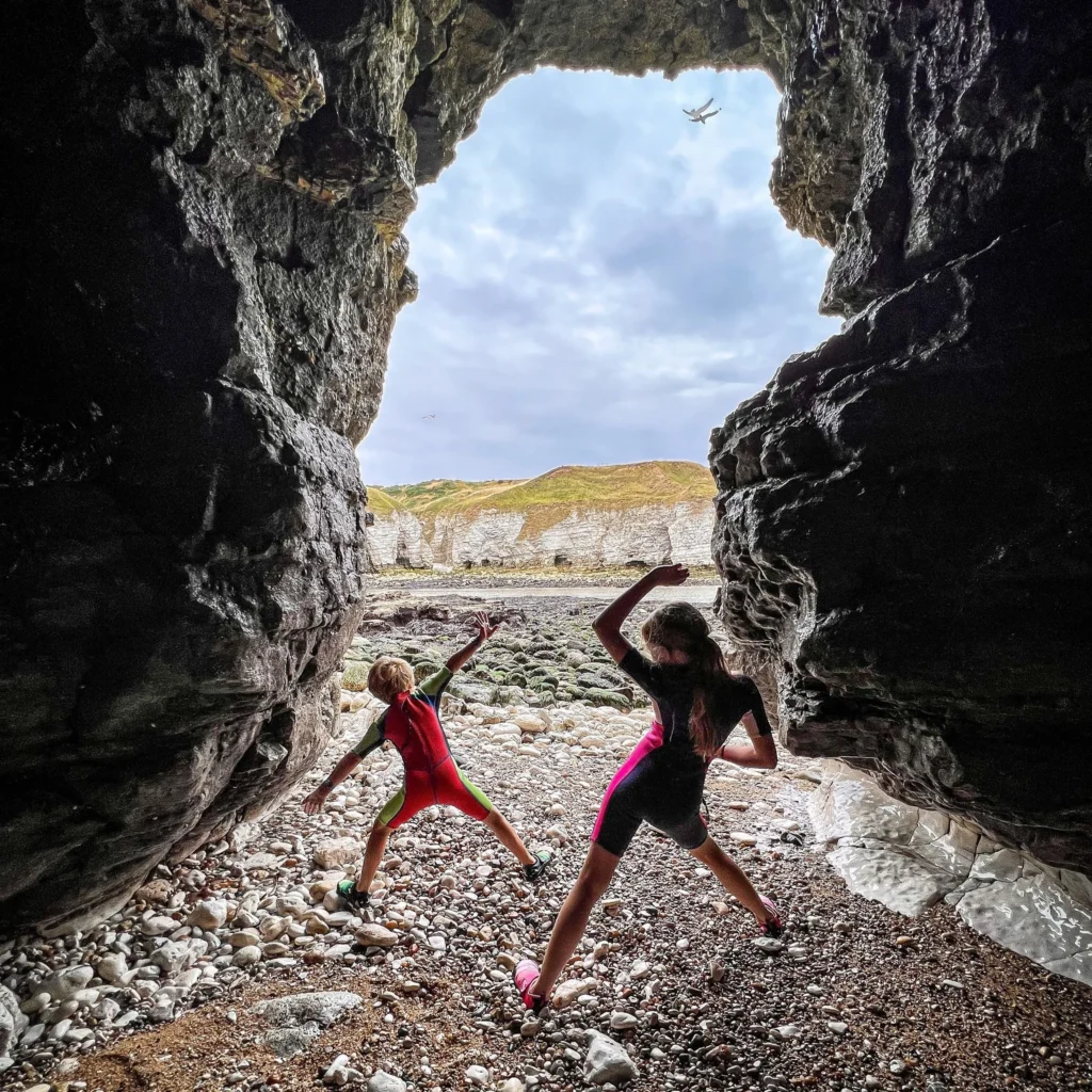 Kids playing in a sea cave at low tide.