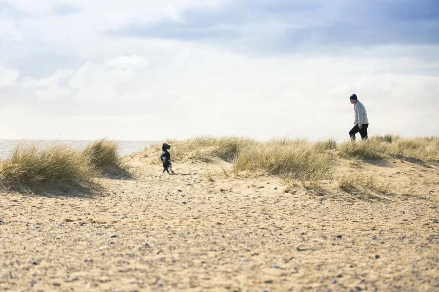 Man and dog in the sand dunes on Caister Beach
