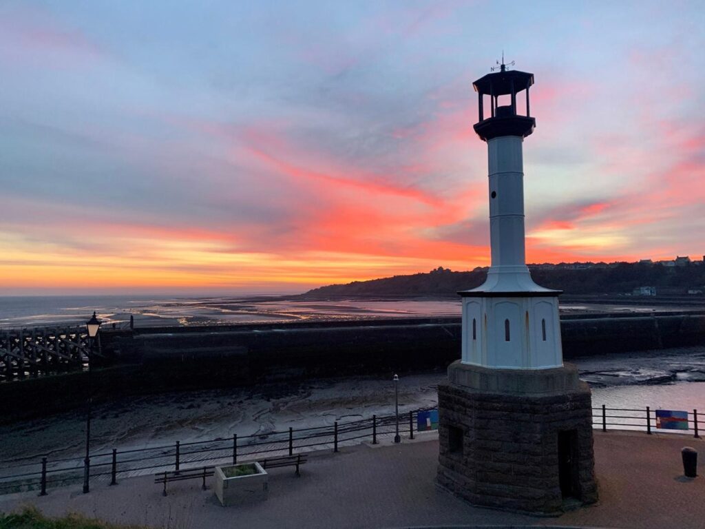 Maryport Lighthouse with a beautiful pink sky as the sun sets over the beach