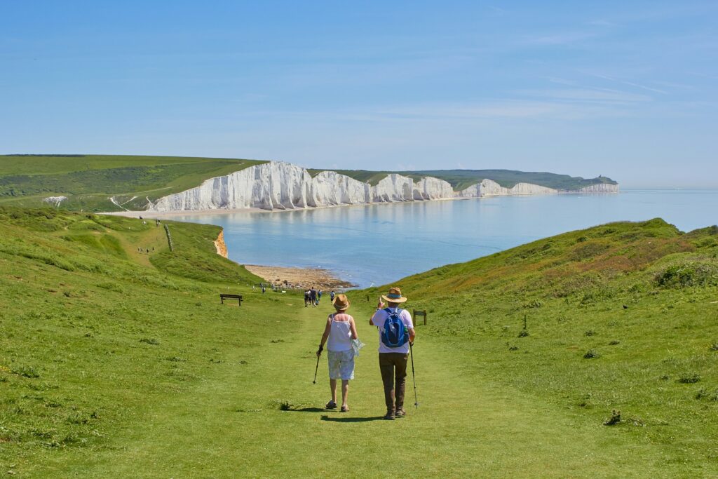 A couple walking on the England coastal path towards the Seven Sisters in East Sussex