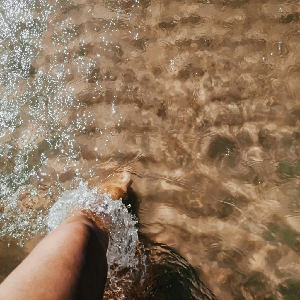 Looking down at a foot paddling in the cold sea water